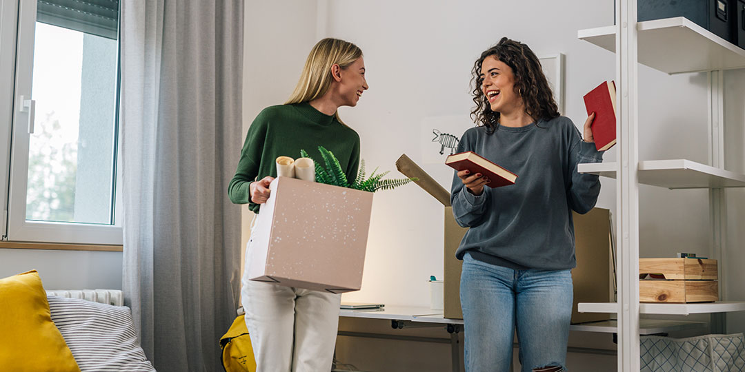 Two female college students greet eachother on their first day back in the dorm.